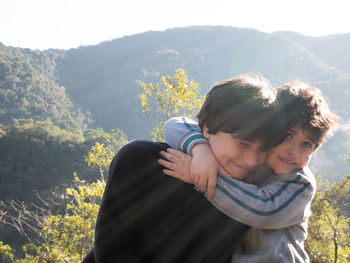 View of brothers hugging in nature with flares.