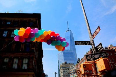 Low angle view of balloons and road sign against one world trade center