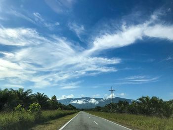 Road by trees against sky