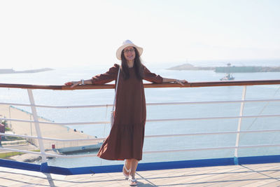 Low angle view of beautiful woman standing on cruise ship deck against clear sky and ocean