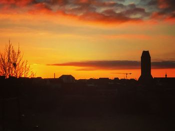 Silhouette built structure against orange sky