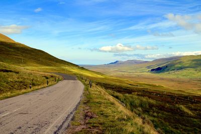 Road leading towards mountains against sky