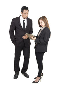 Full length of a smiling young woman standing against white background