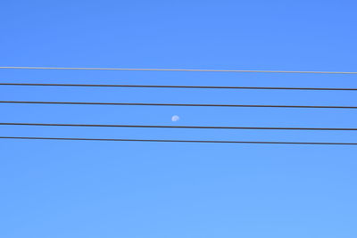 Low angle view of power lines against blue sky