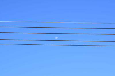 Low angle view of power lines against blue sky