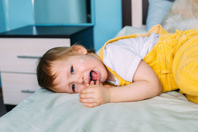 The child is naughty, lying on bed, screaming and crying