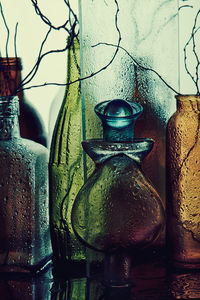 Close-up of old bottles on table against wall