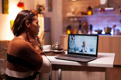 Woman using phone while sitting on table