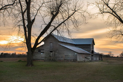 Barn on field against sky during sunset