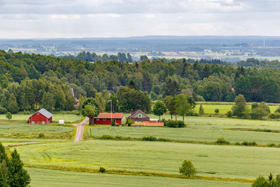 Scenic view of field by trees and houses against sky