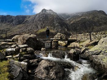 Water flowing through rocks on mountain against sky