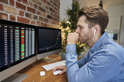 Side view of man using mobile phone while sitting on table