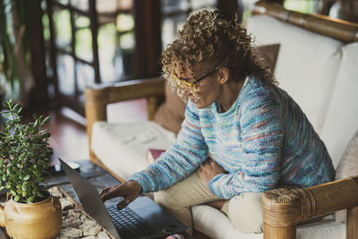 Mature woman using laptop while sitting on sofa at home