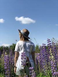Rear view of woman standing on field against sky