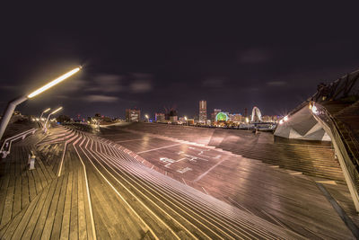 Light trails on street amidst buildings against sky at night