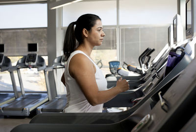 Side view of woman on treadmill in gym