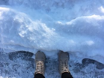 Low section of person standing on snow covered field