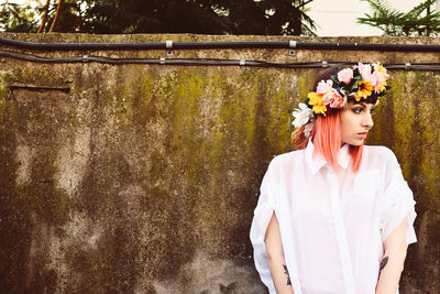 Young woman standing against wall