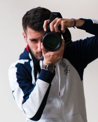 Close-up of man photographing with camera against white background