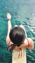 High angle view of woman sitting on diving platform over sea