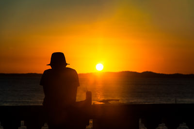 People are seen, in silhouette, enjoying the sunset from the balustrade praia da barra 