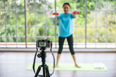 Behind the scene. live woman exercise dumbbell by phone
