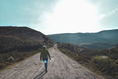 Rear view of man on mountain road against sky