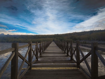 Empty boardwalk leading towards sky