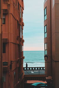 Sea seen through buildings against sky