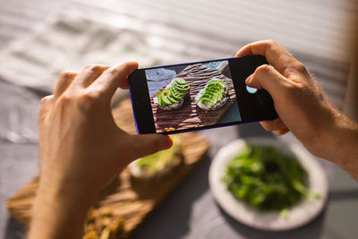 Midsection of person holding mobile phone at table