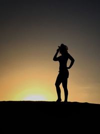 Silhouette woman standing against sky during sunset