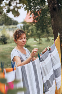 Young woman holding umbrella standing against trees