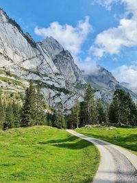 Scenic view of road by mountains against sky