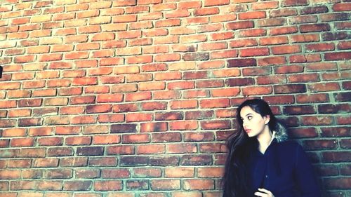 Woman standing against brick wall