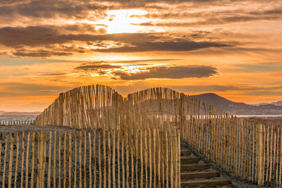 Scenic view of wooden fence at beach against dramatic sunset sky at saint tropez south of france