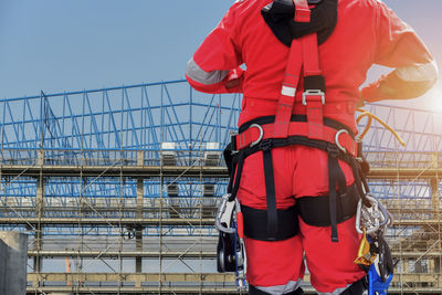Rear view of man working on railing against sky