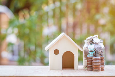 Close-up of model home with stacked coins on table