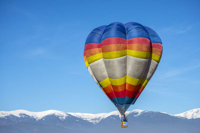 Hot air balloons flying over snowcapped mountains against sky