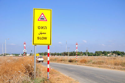 Sign by road against sky