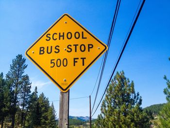 Low angle view of road sign against blue sky