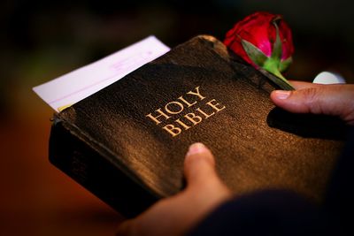 Cropped hands holding bible with rose