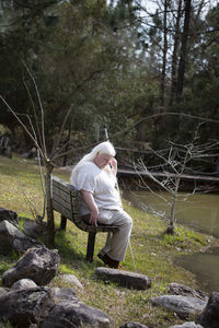 Blind woman sitting on a bench near a pond, shot at a tilted angle