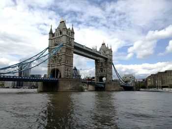 Tower bridge over river against cloudy sky