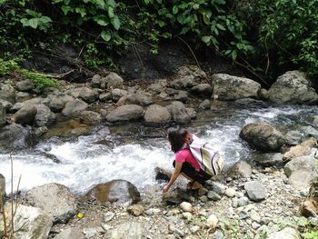 Woman sitting on rock by river