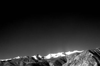 Low angle view of snowcapped mountains against clear sky