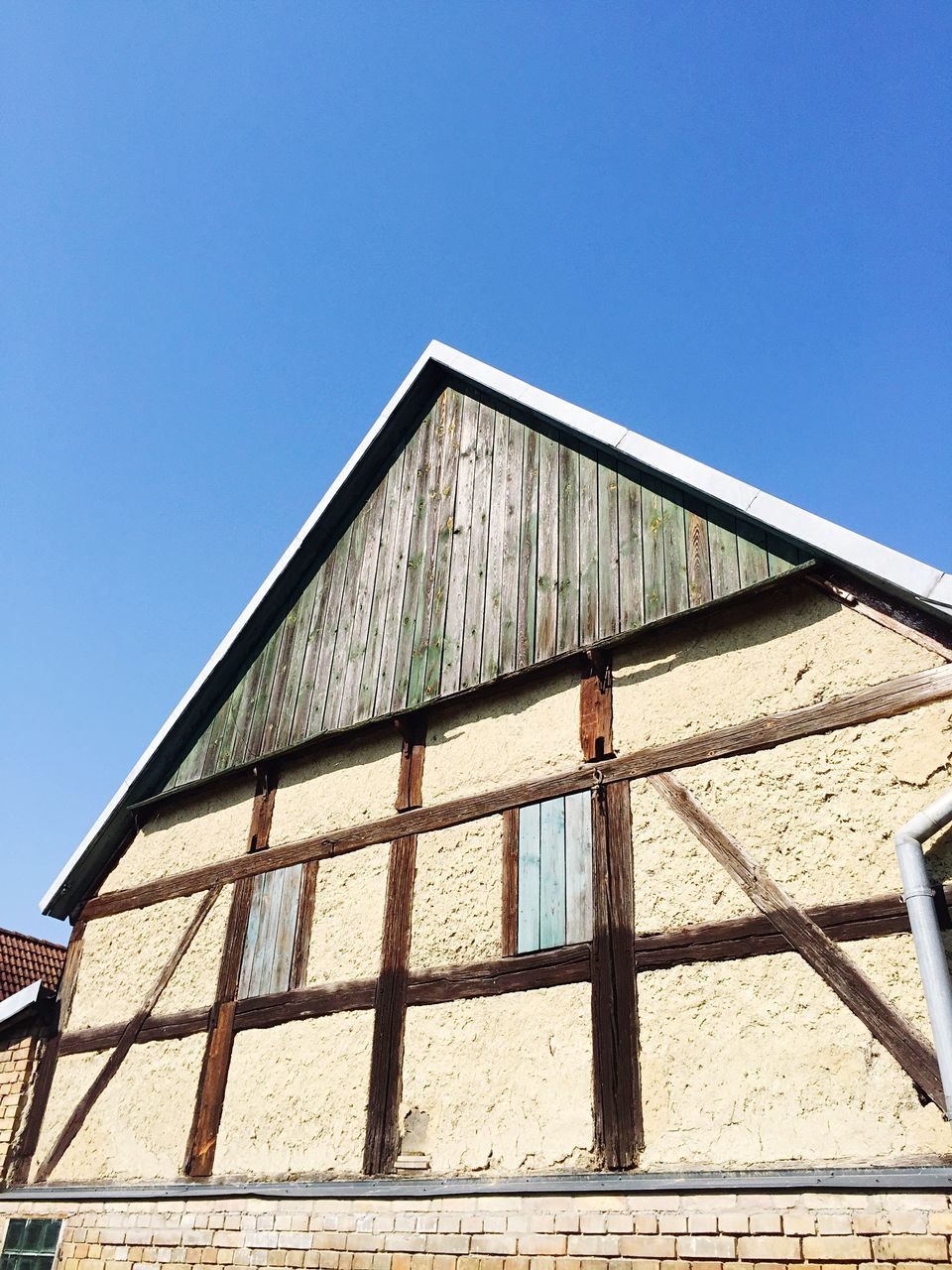 architecture, built structure, building exterior, clear sky, low angle view, blue, copy space, building, window, sunlight, day, outdoors, residential structure, no people, wall - building feature, pattern, shadow, roof, house, high section