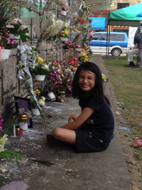 Portrait of smiling woman sitting on sidewalk