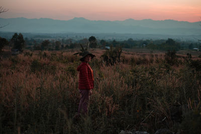Man standing on field against sky during sunset