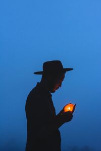 Side view of man standing against blue sky