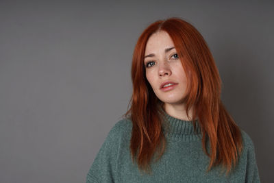 Portrait of young woman against gray background